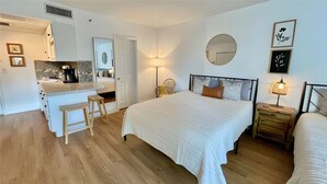 Une chambre à coucher avec un grand lit, des tables de chevet, un miroir et un petit bureau.