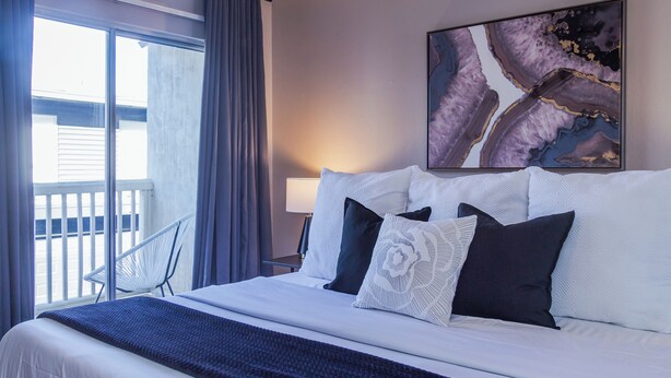 A hotel room with a large bed, a chair by the window, and a painting on the wall. - 3BR The Montrose Collective D, Walk to Food & Fun! ★★★★★ (Houston)