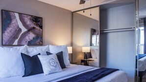 A modern bedroom with a large bed, a nightstand, a lamp, and a mirror. - 3BR The Montrose Collective D, Walk to Food & Fun! ★★★★★ (Houston)