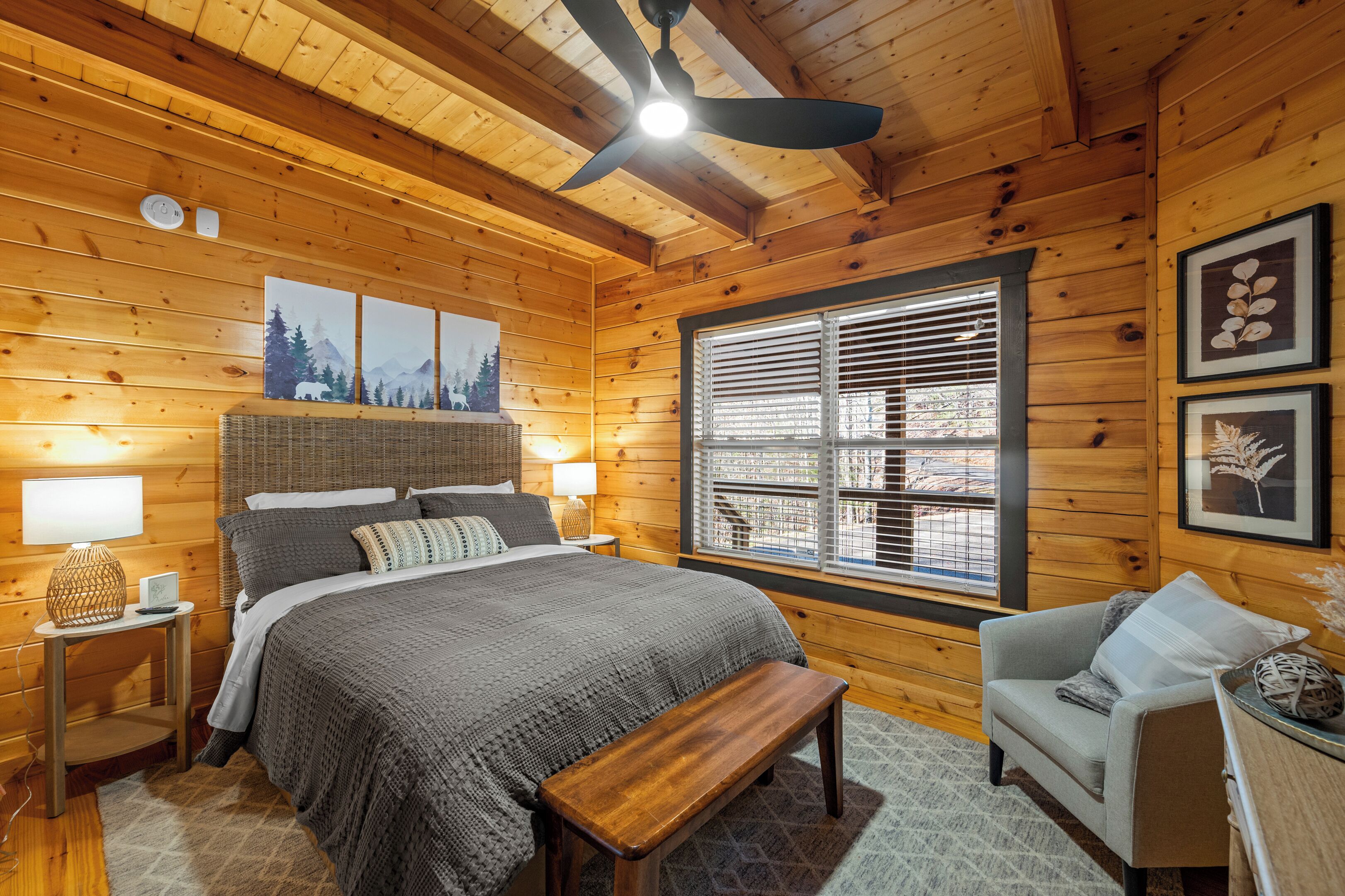 Een gezellig houten slaapkamer met een bed, een bankje en een raam met zonwering.