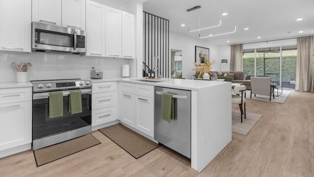 A modern kitchen with white cabinetry, a built-in oven, and a central island.