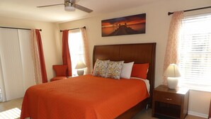 Een slaapkamer met een groot bed, een houten hoofdbord, twee nachtkastjes met lampen en een schilderij aan de muur.