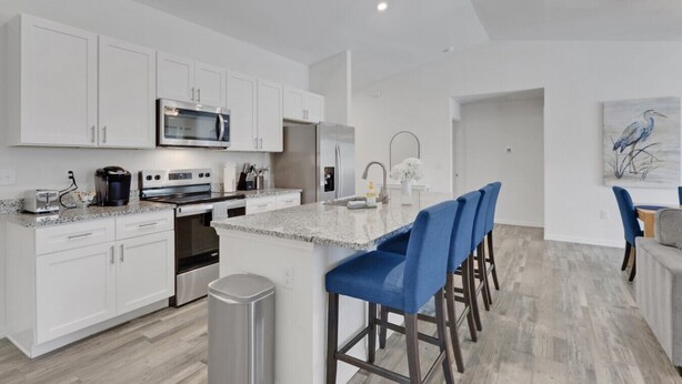 A modern kitchen with white cabinets, stainless steel appliances, and a granite countertop.