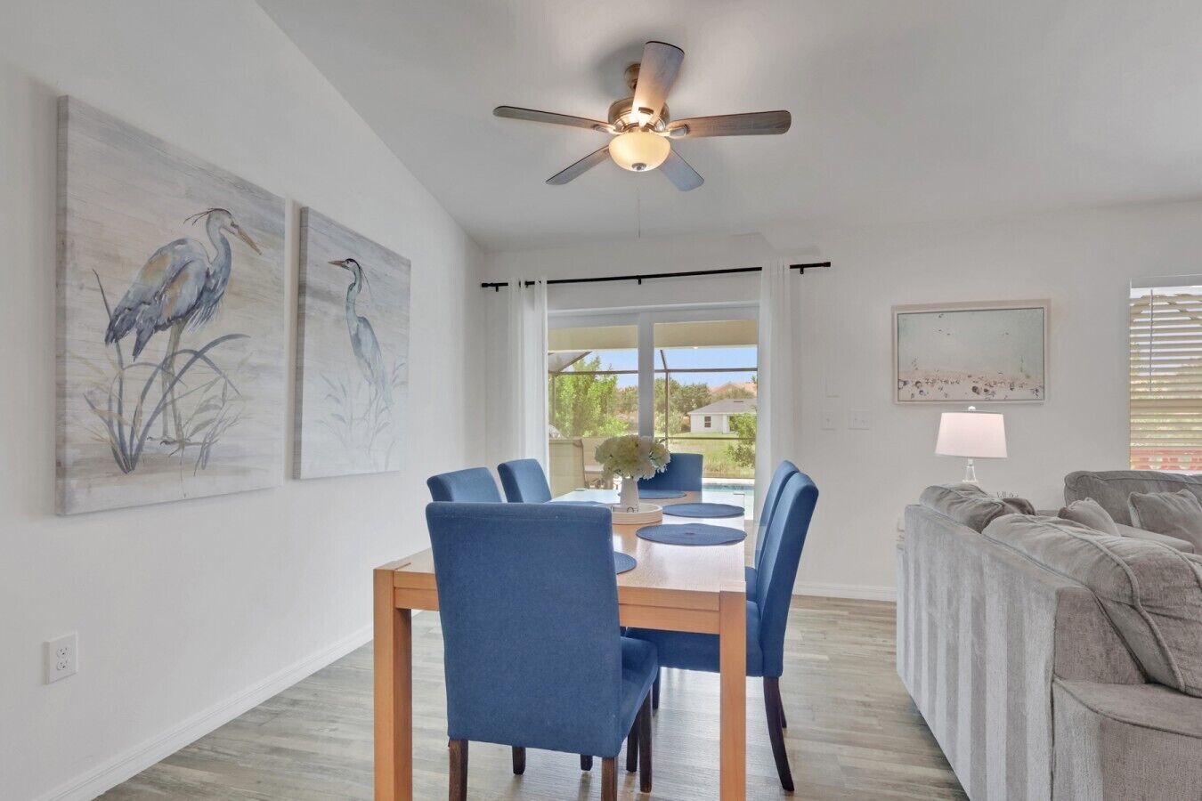 A dining area with a table and chairs, a ceiling fan, and artwork on the walls.