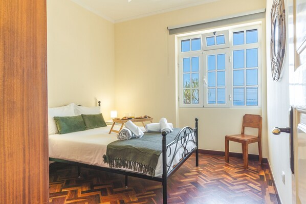 Un dormitorio con cama, una silla, una ventana y una puerta.