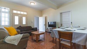 A living room with a sofa, a coffee table, and a dining area with a table set for four.