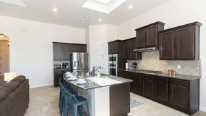 Una cocina moderna con armarios de madera oscura, electrodomésticos de acero inoxidable y una isla central con taburetes.
