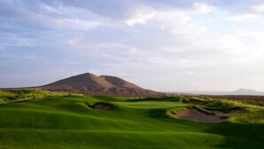 Un campo de golf con una montaña al fondo.