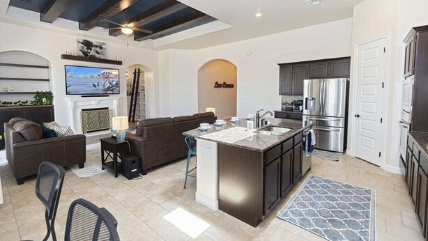 Una cocina moderna con una isla central, muebles oscuros y electrodomésticos de acero inoxidable.