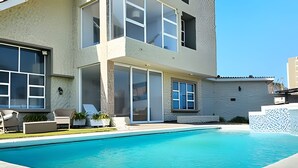 A modern two-story house with a swimming pool, large windows, and outdoor seating. - Casa de playa a 4 cuadras del mar (Puerto Colombia)