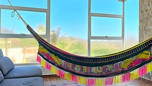 A hammock in a room with large windows and a view of the outdoors. - Casa de playa a 4 cuadras del mar (Puerto Colombia)