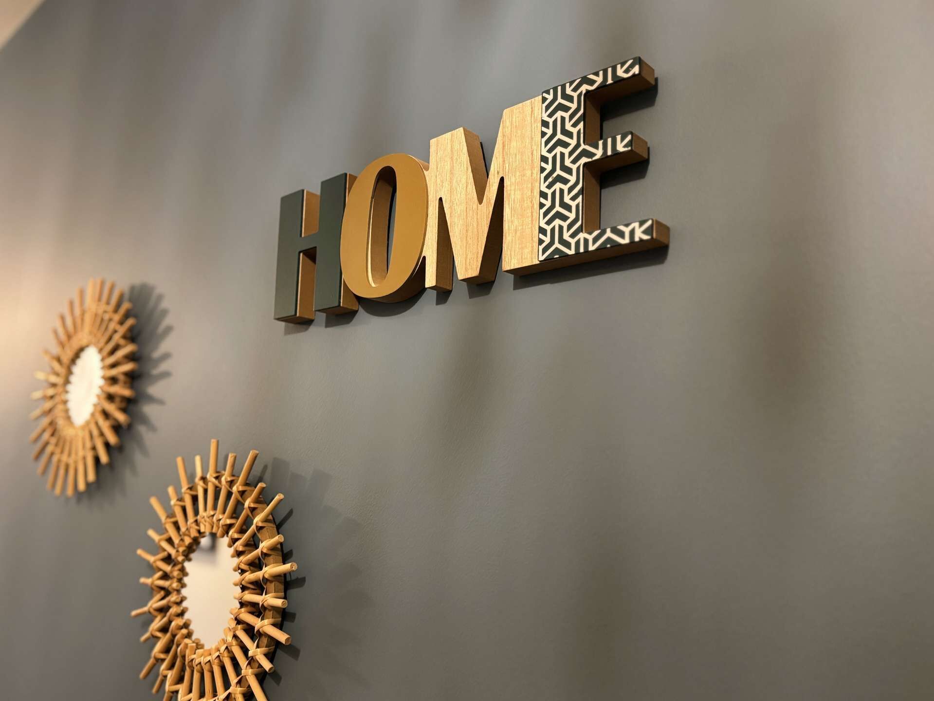 Eine Wand mit dem Wort "HOME" in großen Buchstaben, umgeben von dekorativen Holzelementen.
