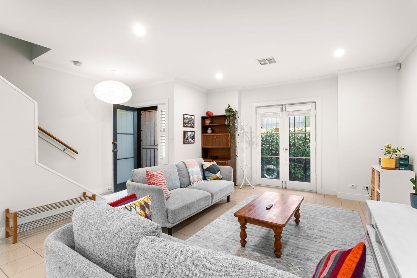 A modern living room with a grey sofa, wooden coffee table, and a staircase.