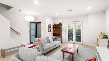 A modern living room with a grey sofa, wooden coffee table, and a staircase.
