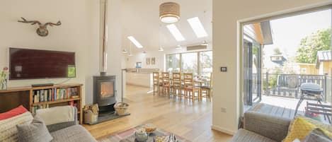 A spacious living room with a fireplace, a television, and a large window offering a view of the outdoors.