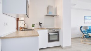 A modern kitchen with white cabinetry, a stainless steel oven, and a wooden countertop.