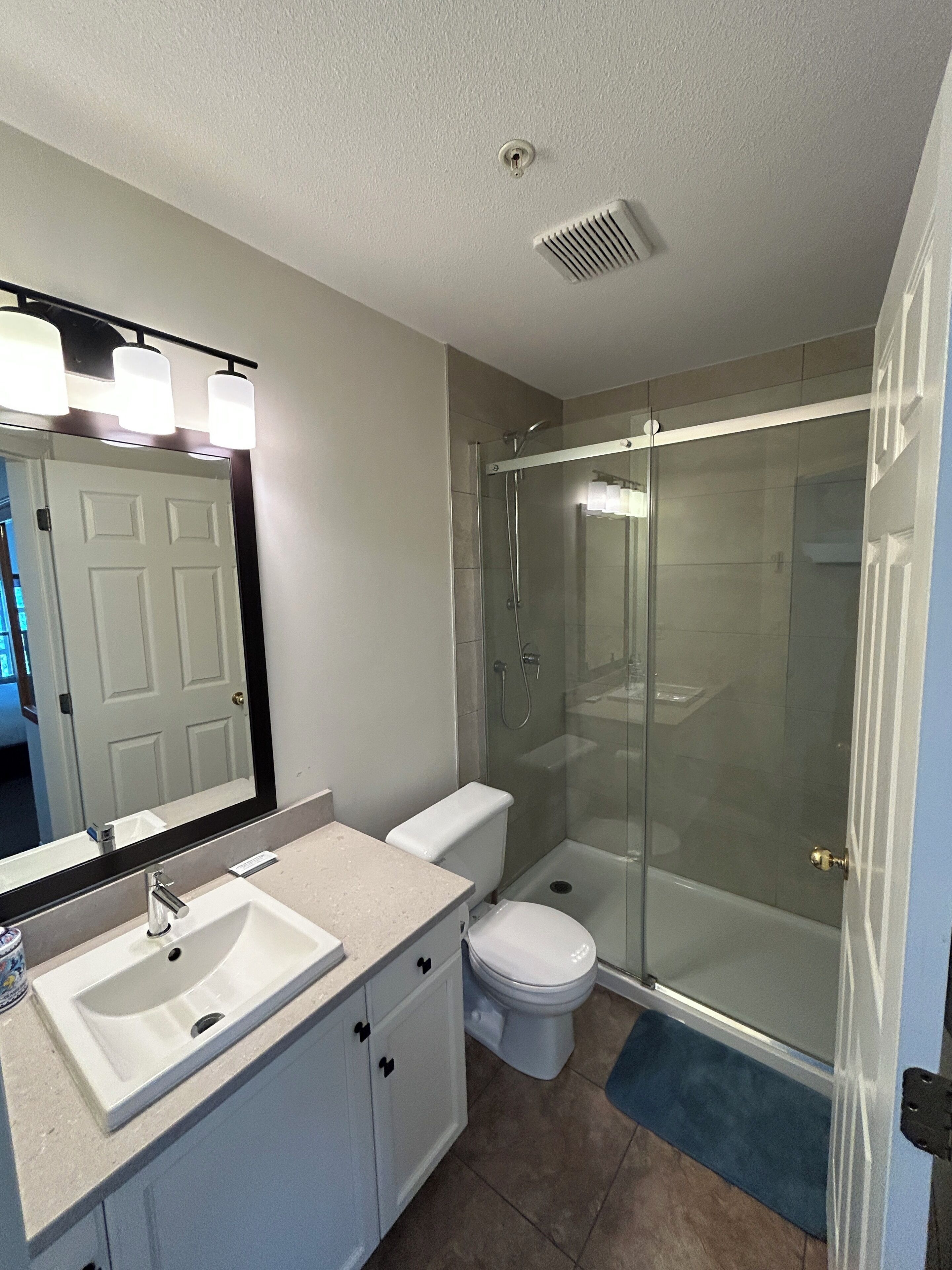 A bathroom with a sink, toilet, and glass-enclosed shower.