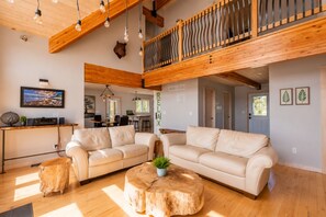 A spacious living area with a large sofa set, a wooden coffee table, and a dining area in the background. - Custom Designed Cottage on Lake Huron (Tobermory)