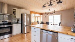 Una cocina moderna con electrodomésticos de acero inoxidable, suelo de madera y una isla grande con asientos.