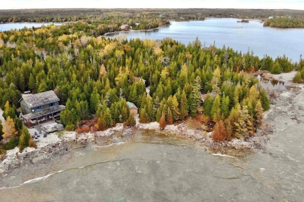 A cabin surrounded by dense forest and a lake.