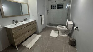 Ein modernes Badezimmer mit einem Holzkosmetikschrank, einem großen Spiegel, einer Toilette und einer Duschkabine.