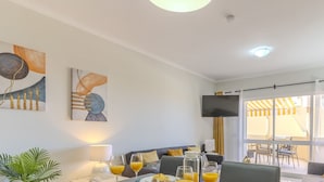 Una sala de estar moderna con un sofá, una mesa de centro con bebidas y obras de arte en las paredes.