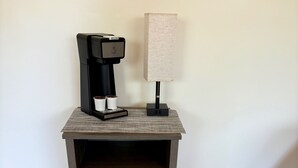 Et lille natbord med kaffemaskine og lampe.