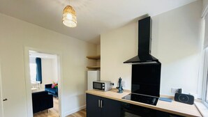 A modern kitchen with black cabinets, a microwave, a toaster, and a stove.