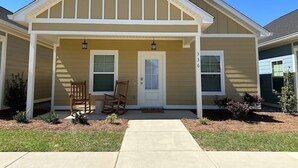 A two-story house with a front porch, a door, and two windows. - The Cottages 3  2BR2BA Dothan Pet Friendly Gorgeous Pool, Pickle Ball court, Gym (Dothan)