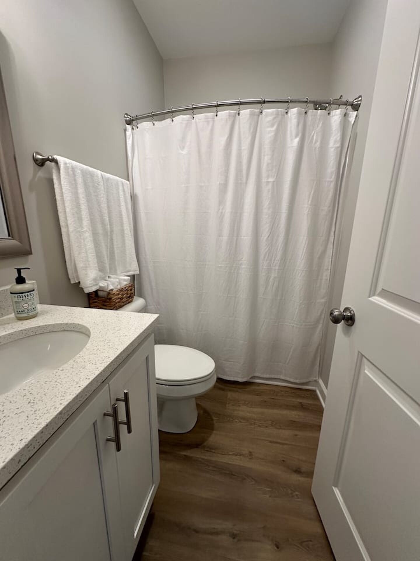 A bathroom with a white toilet, a sink with a soap dispenser, and a shower curtain.