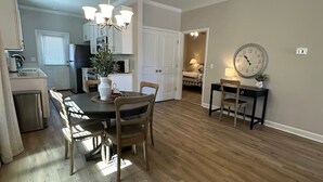 A modern kitchen with a dining area, wooden flooring, and a clock on the wall. - The Cottages 3  2BR2BA Dothan Pet Friendly Gorgeous Pool, Pickle Ball court, Gym (Dothan)
