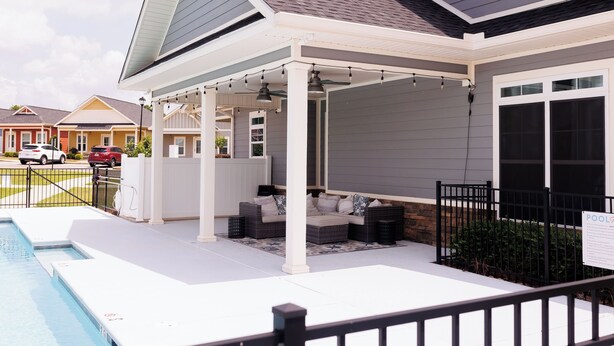 A covered outdoor seating area with a pool, a fenced patio, and a view of neighboring houses. - The Cottages 3  2BR2BA Dothan Pet Friendly Gorgeous Pool, Pickle Ball court, Gym (Dothan)
