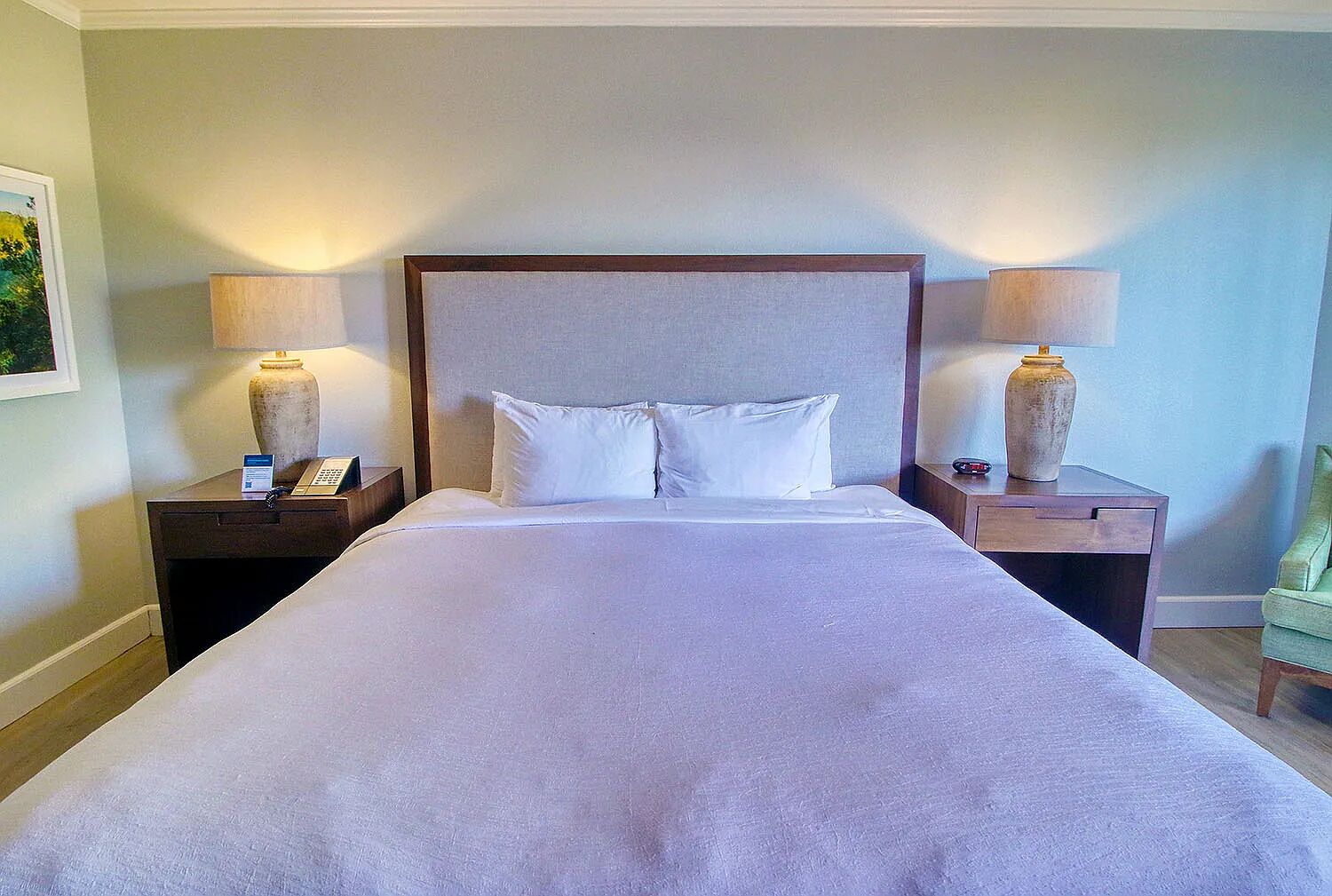 A hotel room with a large bed, two nightstands, and lamps.