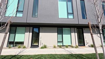 A modern building with large windows, a flat roof, and a gravel driveway.