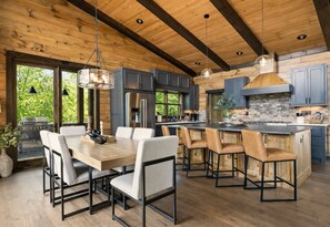 A modern kitchen with wooden beams, a central island, and a dining area with chairs.
