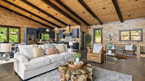A spacious living area with a white sofa, a glass coffee table, and a wooden ceiling. - Sippin on Sunsets: Ultra Luxe Escape • Epic Views • Hot-Tub  • Secluded Comfort (Cherry Log)