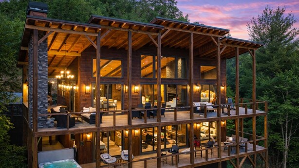 A multi-level wooden cabin with a hot tub, outdoor seating, and a large windowed living area. - Sippin on Sunsets: Ultra Luxe Escape • Epic Views • Hot-Tub • Secluded Comfort (Cherry Log)