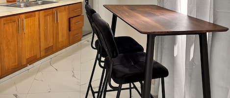 Una cocina moderna con armarios de madera, un refrigerador de acero inoxidable, un lavabo y una mesa de comedor con sillas.