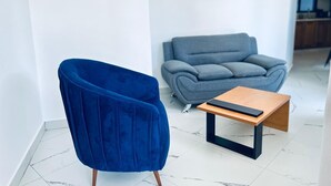 Ein modernes Wohnzimmer mit einem blauen Sessel, einem grauen Sofa und einem Holztisch.