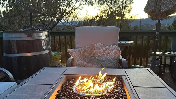 Een terras met een vuurkorf, een stoel en een uitzicht op bomen en bergen.