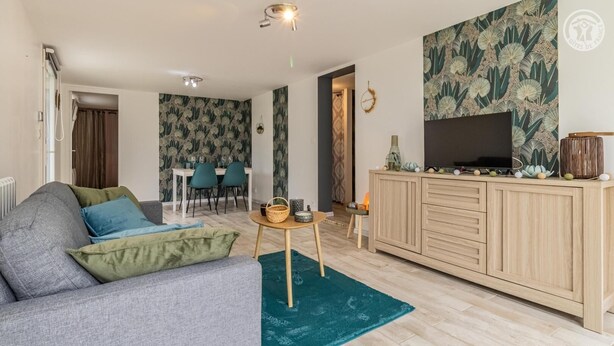 A living room with a sofa, a coffee table, and a TV on a wooden cabinet. There is a dining area with chairs and a table in the background. - VILLA MASANDJO - SAINT ALBAN LEYSSE (SAINT ALBAN LEYSSE)