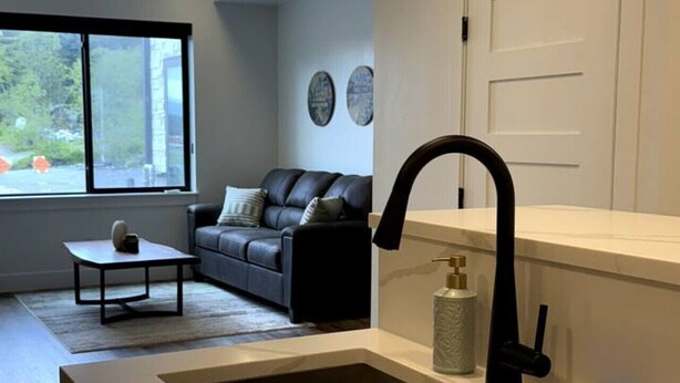 A modern kitchen with a large sink, a dining area with a table and sofa, and a view through a window. - Spacious Accessible Ground Floor Getaway A101 (Juneau)