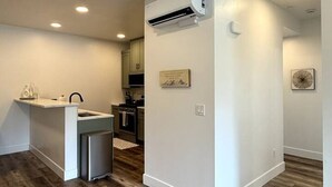 A modern kitchen with a built-in island, white cabinetry, and a central air conditioning unit. - Spacious Accessible Ground Floor Getaway A101 (Juneau)