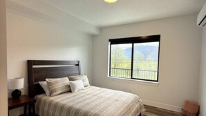A bedroom with a bed, a nightstand, a window with a view, and a ceiling light. - Spacious Accessible Ground Floor Getaway A101 (Juneau)
