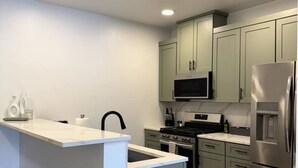 A modern kitchen with a central island, stainless steel appliances, and light-colored cabinetry. - Spacious Accessible Ground Floor Getaway A101 (Juneau)
