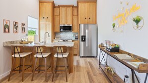 Una cocina moderna con armarios de madera, electrodomésticos de acero inoxidable y un letrero de neón.