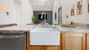 Una cocina moderna con lavavajillas integrado, un lavamanos grande y un armario de madera.
