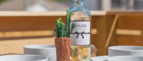 Ein Tisch mit einer Weinflasche, einem kleinen Kaktus und weißen Schalen.
