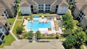 A residential complex with a central swimming pool, multiple balconies, and surrounding greenery. - 1BR Near The Woodlands Pool, Gym & Free Parking (Magnolia)