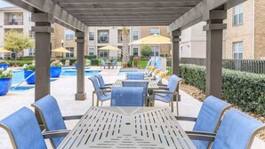 A covered outdoor area with a pool, lounge chairs, and umbrellas. - 1BR Near The Woodlands Pool, Gym & Free Parking (Magnolia)